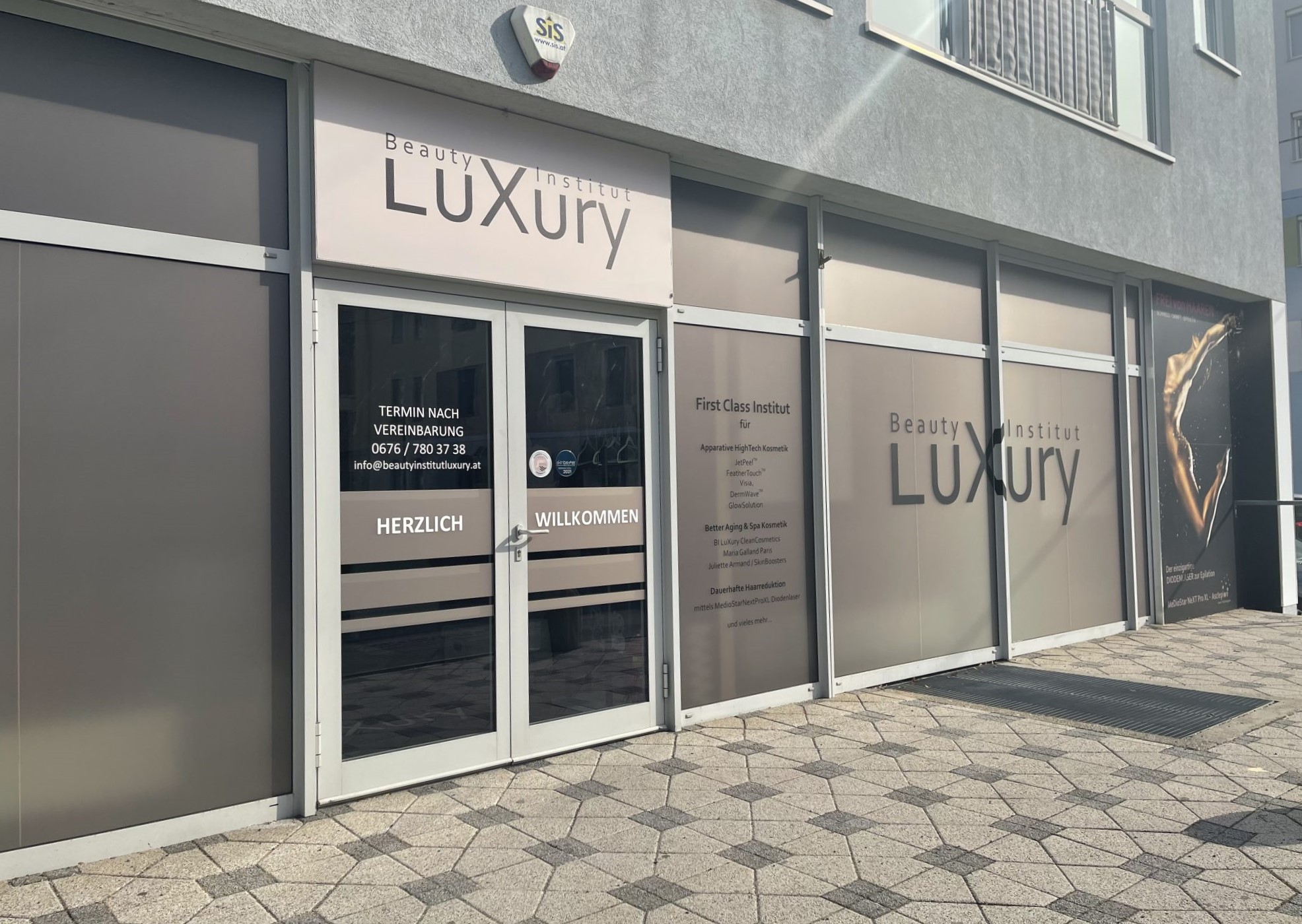 Eingang des Beauty-Institut LuXury in Graz mit Schriftzug und Informationen im Schaufenster